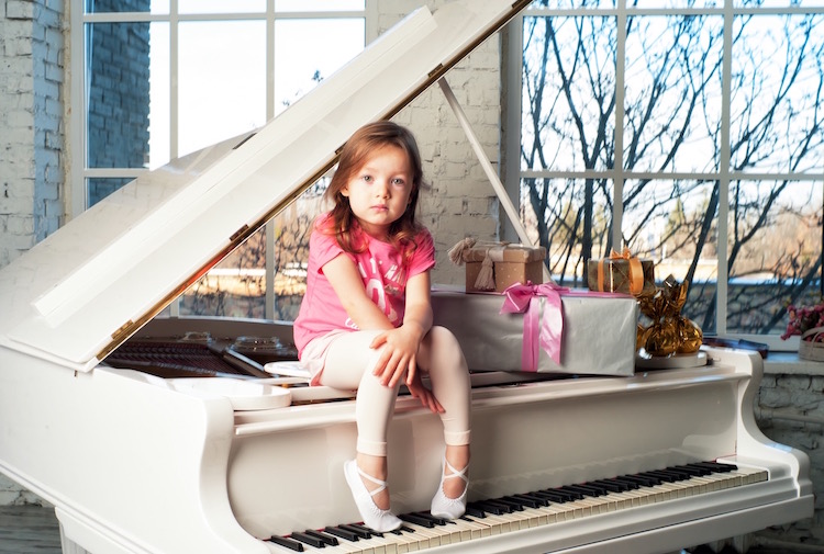 Little girl sits in piano 